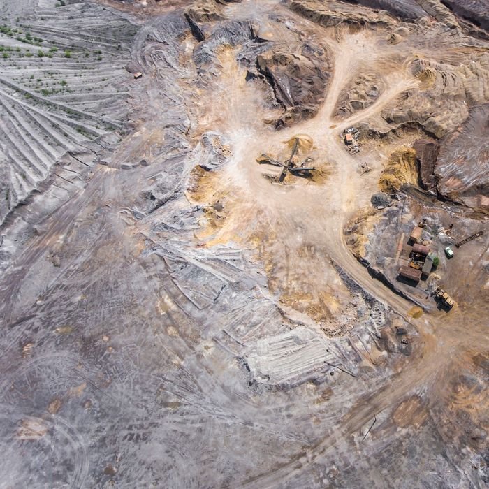 Home An expansive aerial view of a mining site displaying machinery and earth patterns.