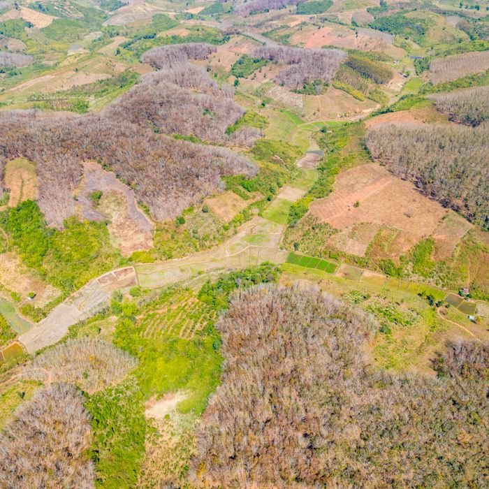 Home A breathtaking aerial view of Kon Tum, Vietnam, showcasing diverse terrain and patchwork of fields.