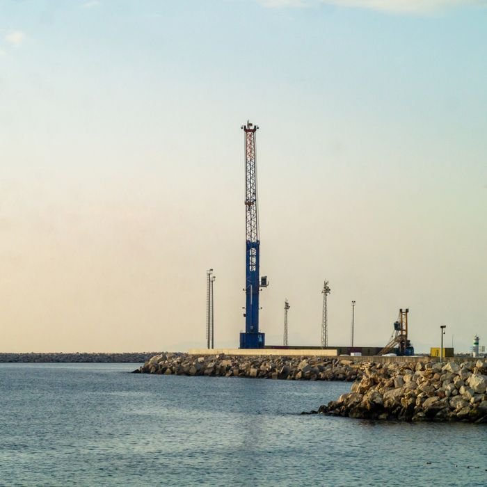 pexels photo 34099347 34099347 Industrial crane at a seaside pier during sunset, capturing a serene coastal landscape.