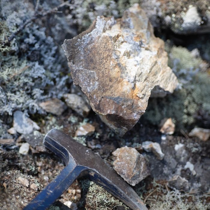 Home Close-up view of a rock and hammer used in geological exploration and mining.